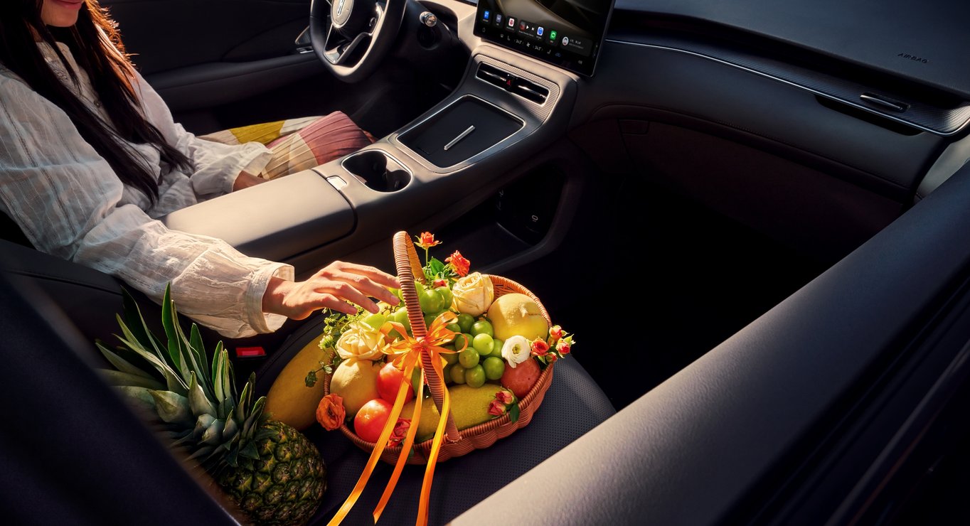 A woman seated in the driver's seat with fresh fruit beside her, showcasing the health-conscious cabin