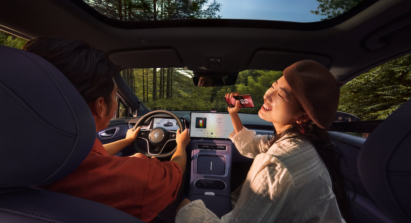 A man and a woman enjoying karaoke without microphones inside the vehicle