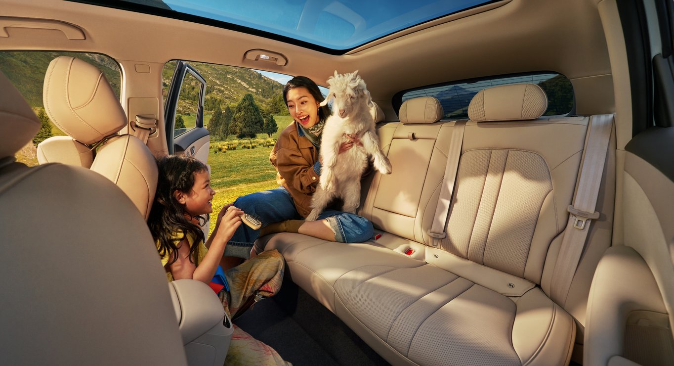 A woman holding a lamb and a child playing in the rear of the SAIC H5, demonstrating the expansive rear seat space