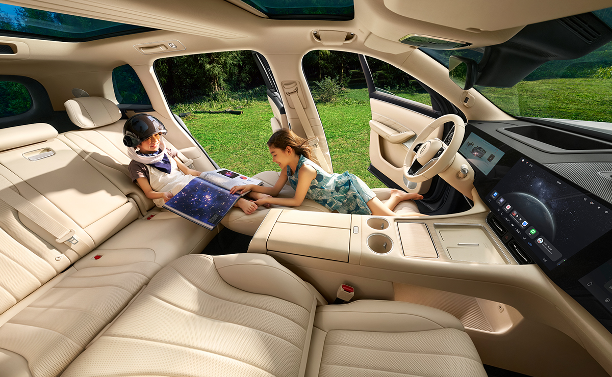 A family of three sitting together on the second-row seats of the AITO M8 in White Sand Apricot after the front seats are folded