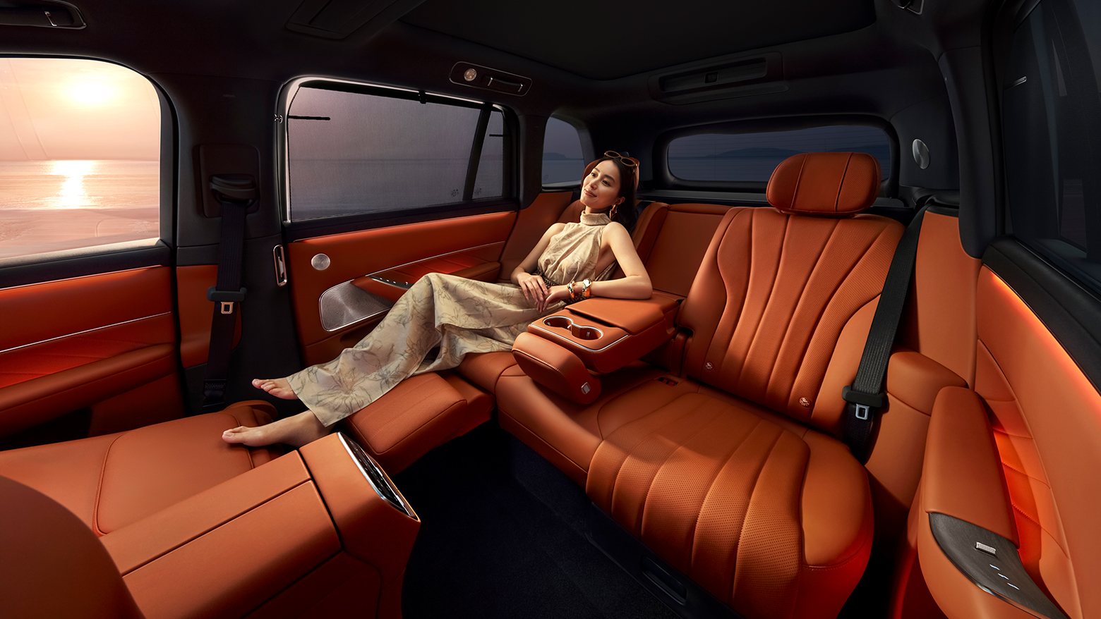 A woman reclining on the unfolded second-row zero-gravity seat in AITO M8 Red Tea Orange