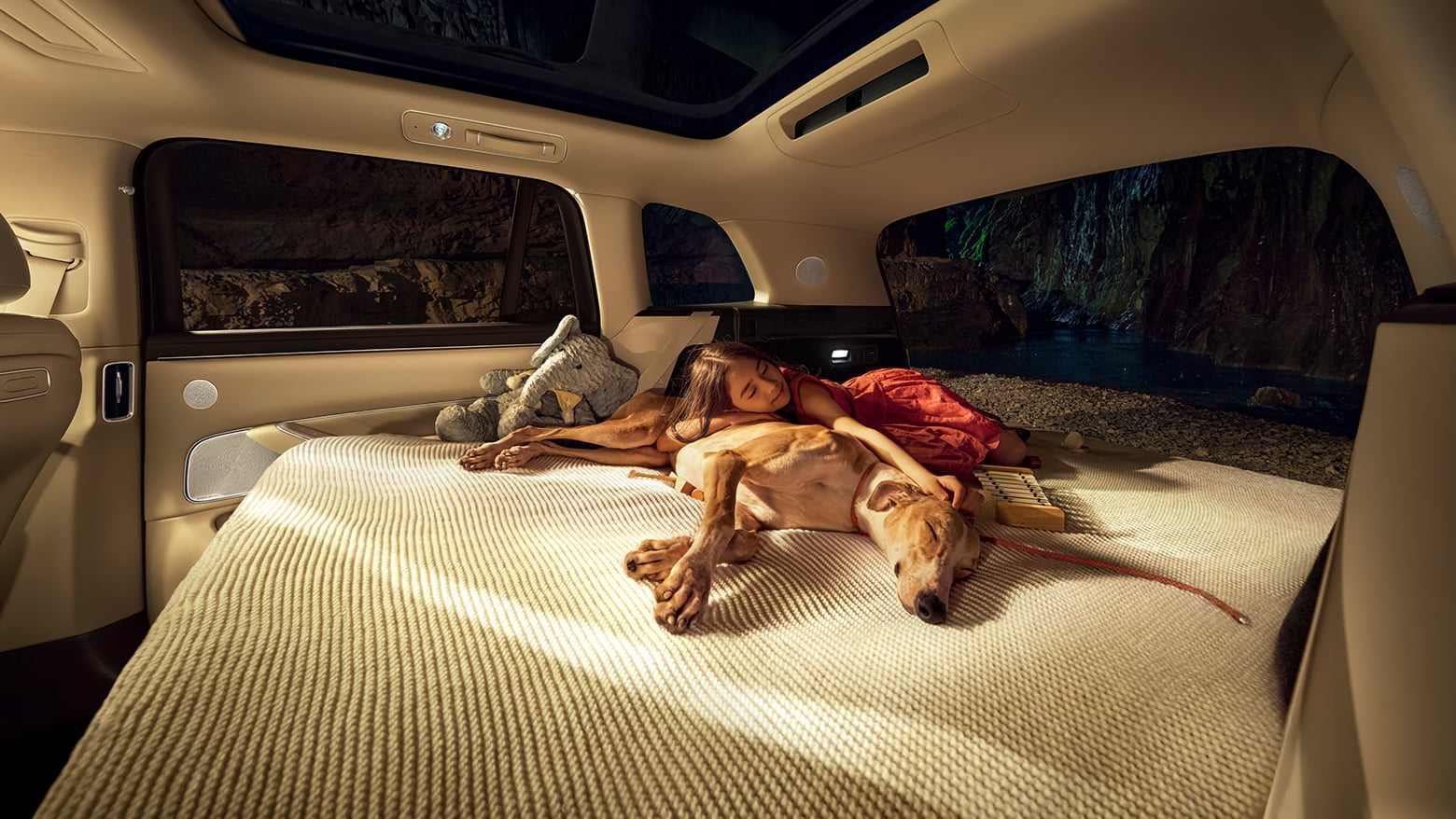 A little girl sleeping with a dog on the unfolded bed of the AITO M8 in White Sand Apricot