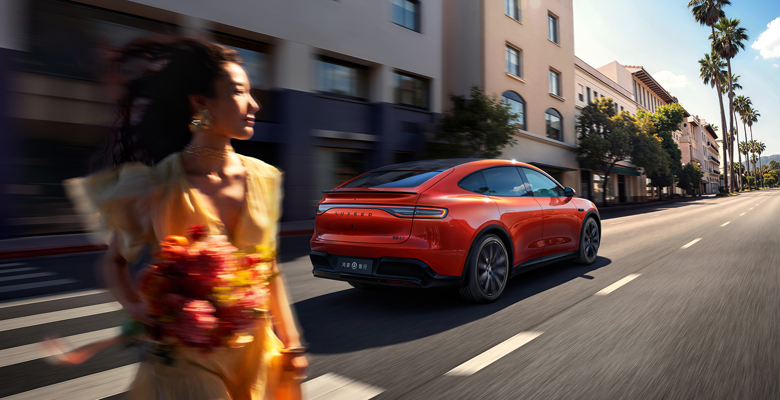 The Luxeed R7 Vibrant Orange EREV drives on the road, showcasing its long-range performance.