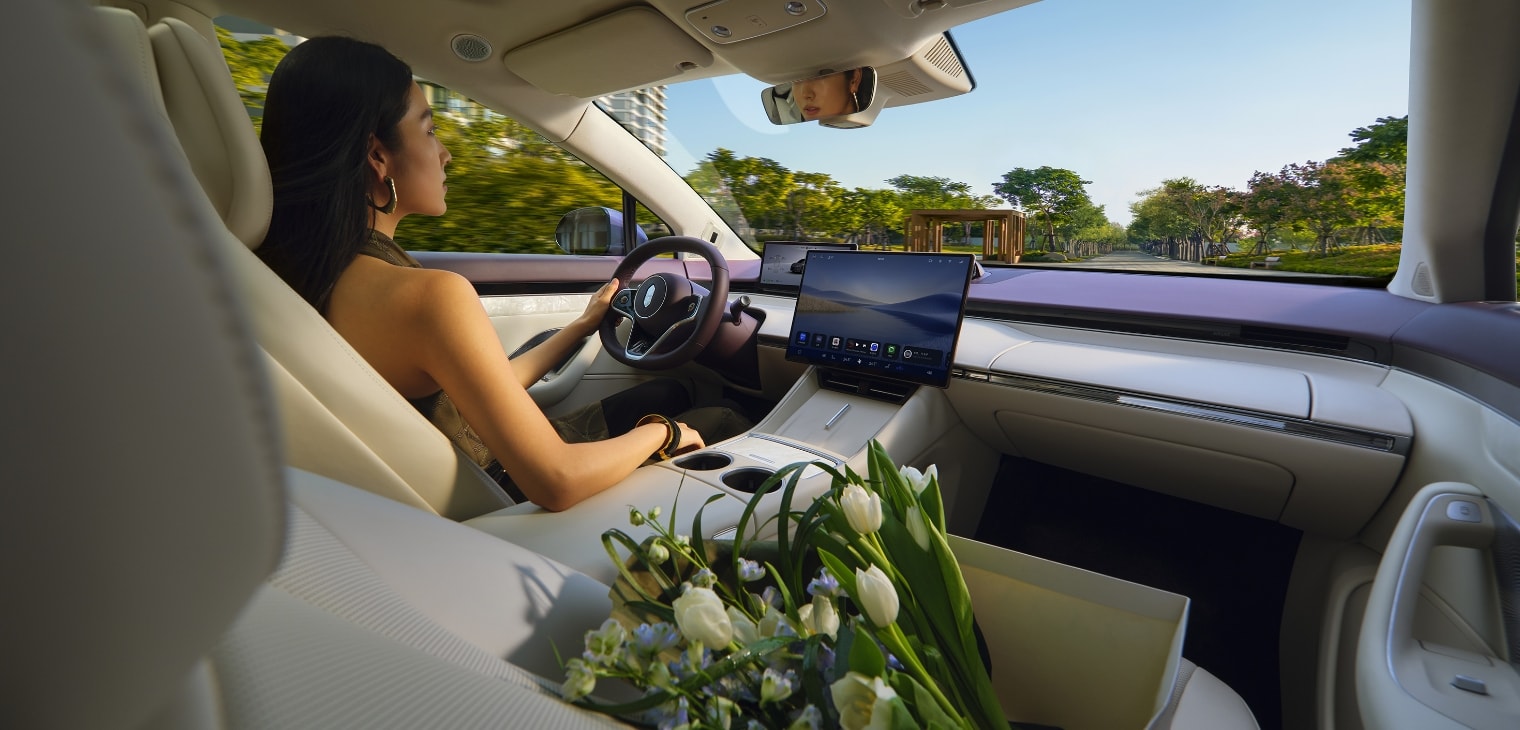 A woman driving the Luxeed R7 with a relaxed demeanor, demonstrating the comfortable in-car environment created by the tri-zone automatic climate control