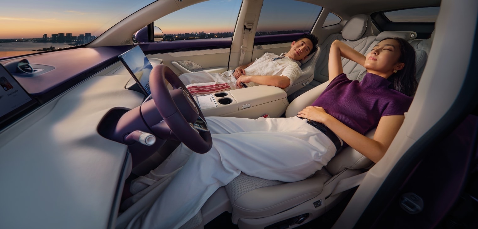 Two people reclining comfortably in the front seats, showcasing the Luxeed R7's dual zero-gravity seats for driver and front passenger