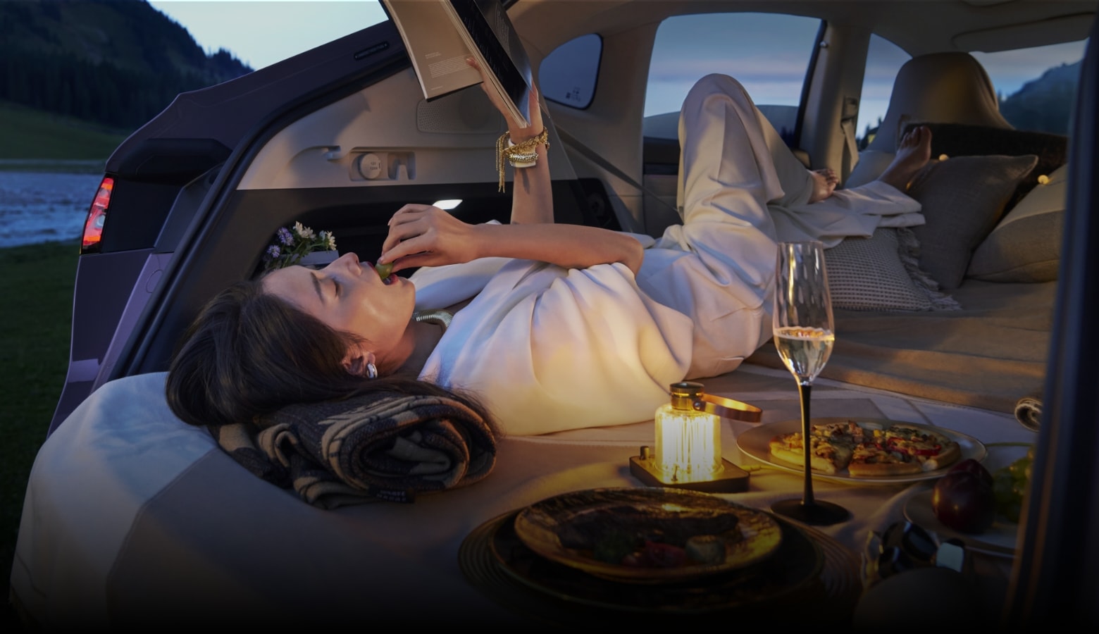 A woman reclining freely in the rear seat, enjoying a reading session, showcasing the Luxeed R7's versatile functionality with rear seats folded flat into a bed